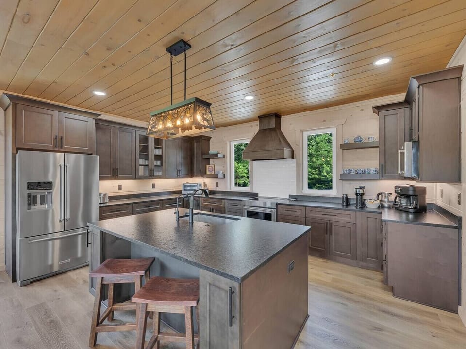 A large island anchors the kitchen, ideal for sharing snacks, setting out buffets, or enjoying casual drinks while dinner simmers.