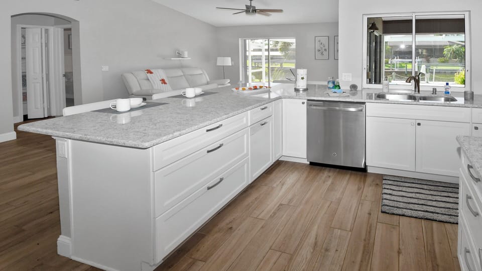 Modern, stylish all-white kitchen with spacious worktop and view of the second living room