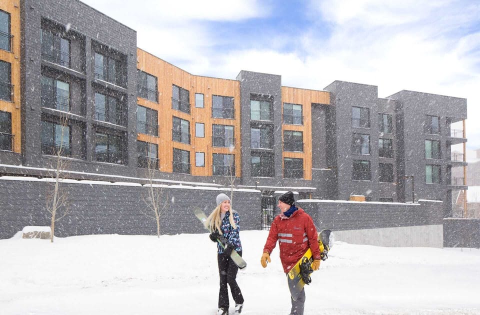 Canyon Haus snowy exterior with couple walking to the lifts.