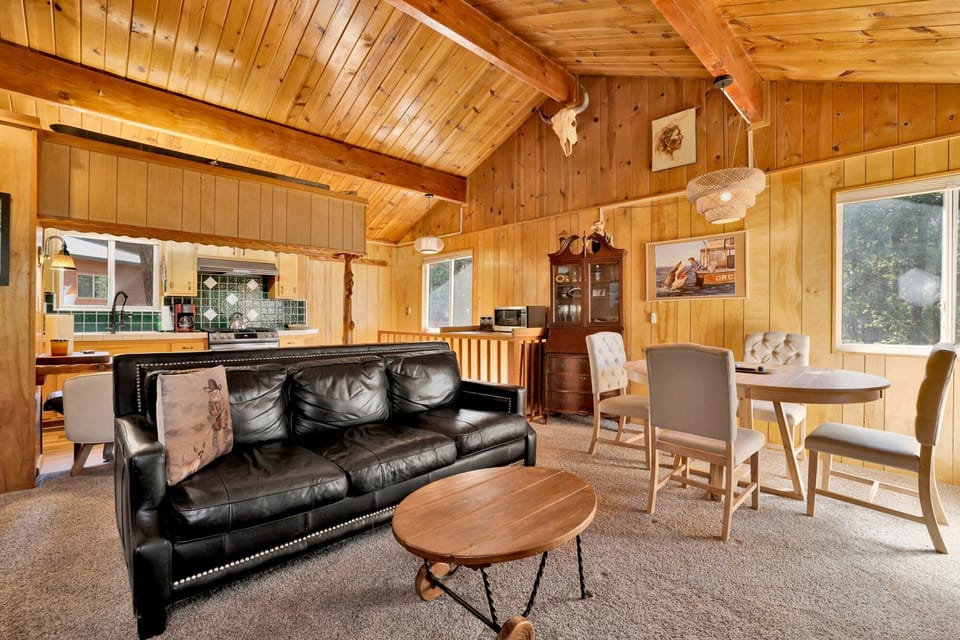 Cozy mountain living room with a stone fireplace, comfy seating, and smart TV—perfect for relaxing evenings, movie nights, and warm cabin vibes after outdoor adventures.