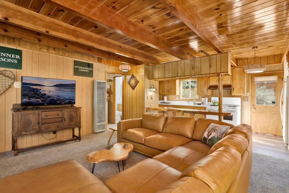 Cozy mountain living room with a stone fireplace, comfy seating, and smart TV—perfect for relaxing evenings, movie nights, and warm cabin vibes after outdoor adventures.