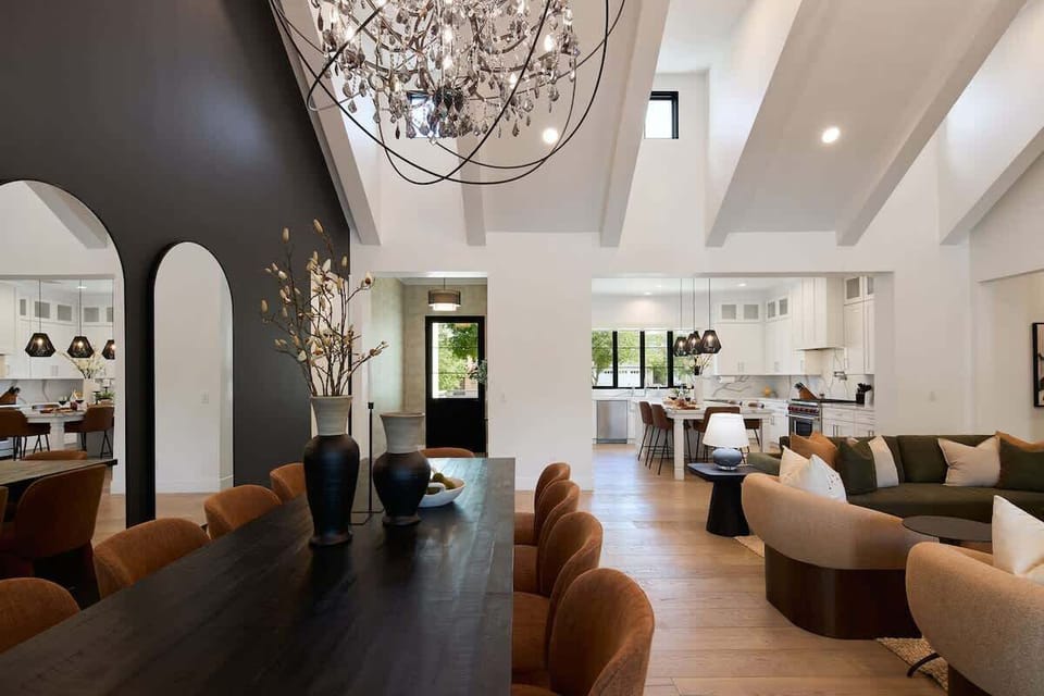 Open living area featuring designer furnishings, a Smart TV, fireplace, dining area, and access to the backyard.
