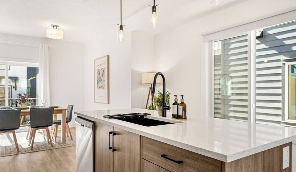 Updated kitchen with large island, black sink, stainless steel appliances, and bright natural lighting