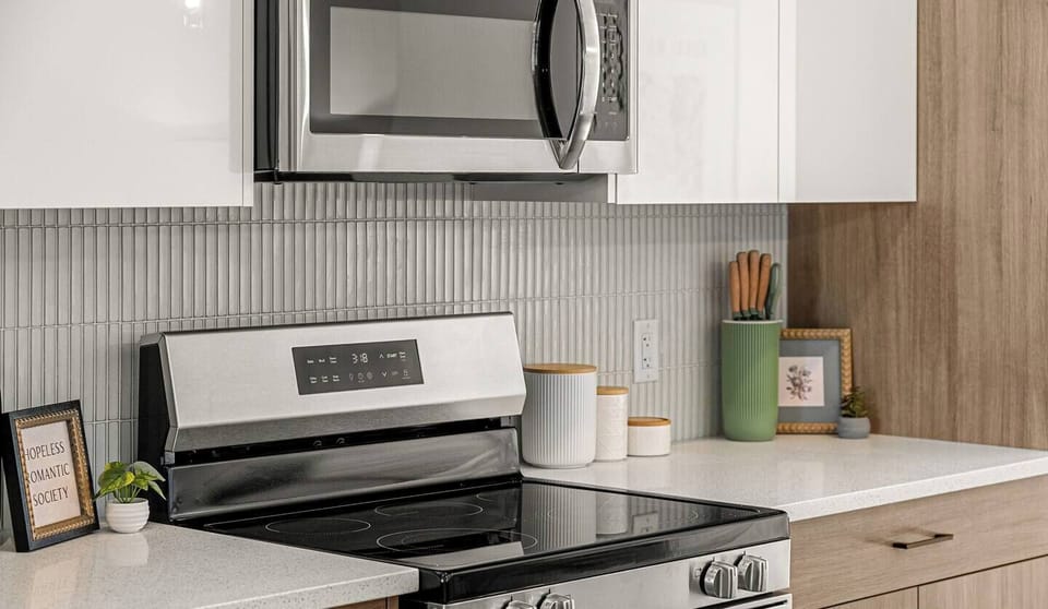 Fully equipped kitchen featuring stainless steel appliances and white countertops