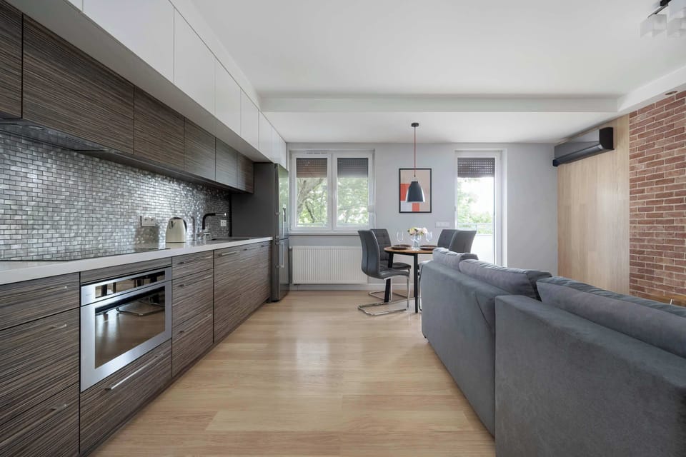 A spacious open-plan living area with a kitchen and lounge. The combination of wood and neutral tones creates a welcoming atmosphere.