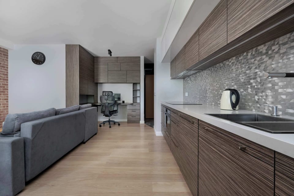 A modern kitchen with sleek cabinetry and a work desk nearby. Perfect for combining home cooking and remote work.