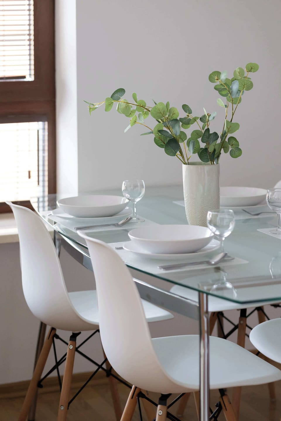 A close-up of the dining table with elegant white chairs. A vase of flowers serves as a delicate centerpiece.