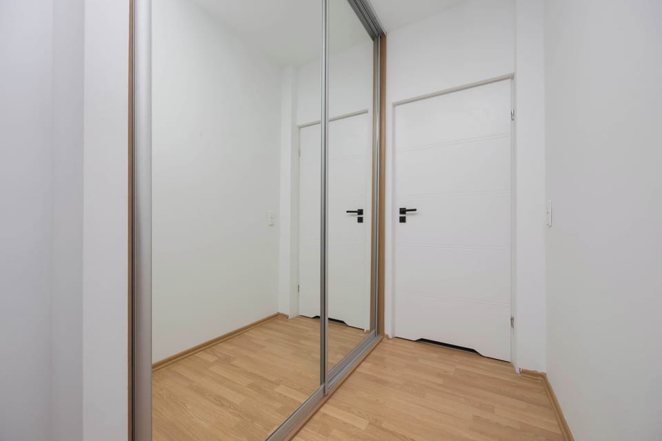 A hallway with built-in wardrobes offering practical storage. The white walls and doors make it clean and simple.