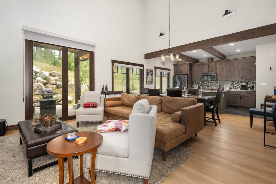 Sink into plush leather seating in your open-concept retreat, where rustic beams meet modern elegance and mountain views frame your perfect getaway.