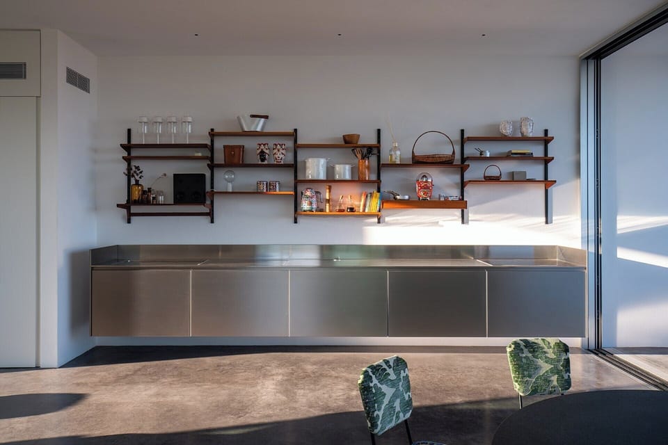 The stainless steel kitchen appears to float above the ground.