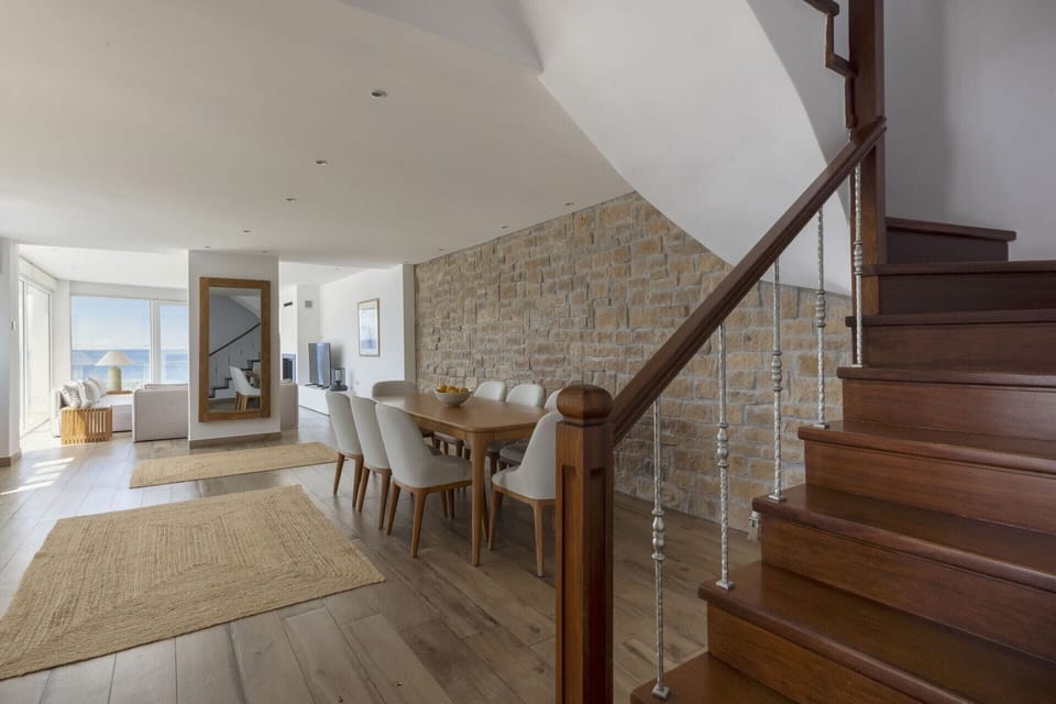 The dining room flows seamlessly into the living room, with the backdrop of the sea.