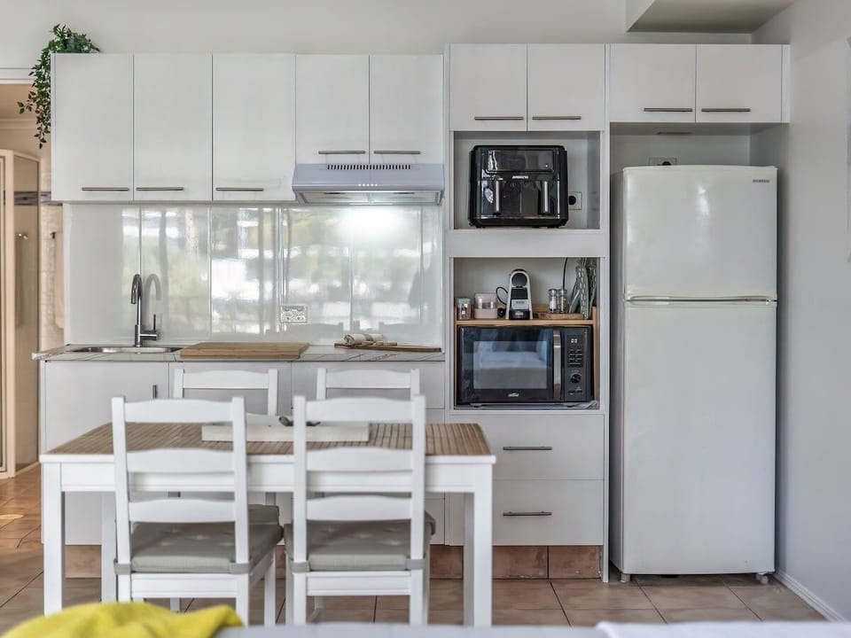 Kitchenette with air fryer, coffee machine, cooktop and dining for four at home.