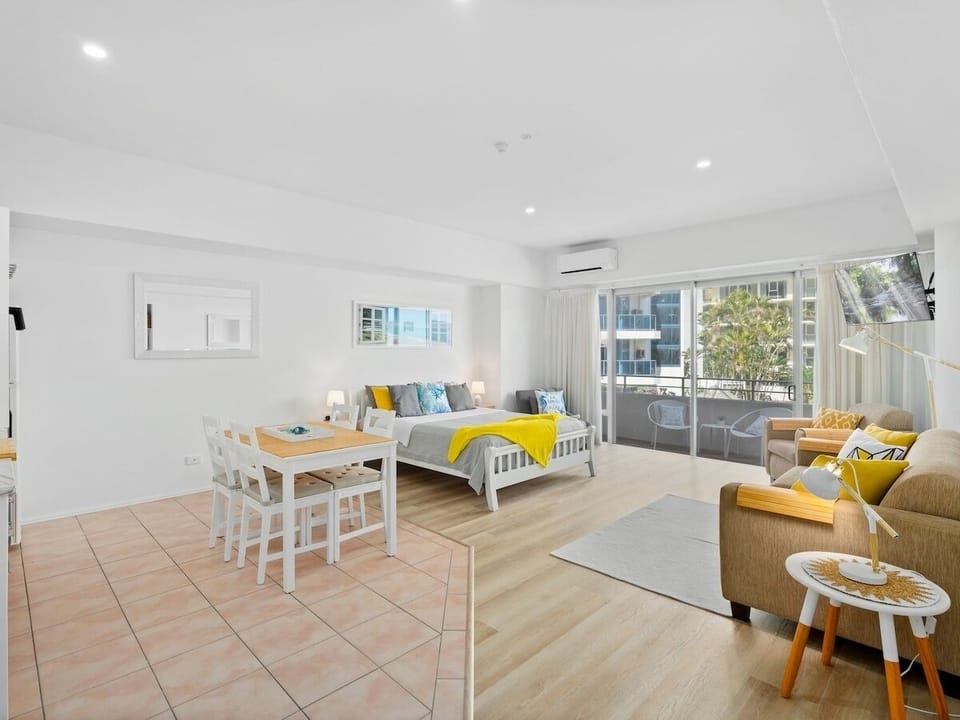 Queen bed, TV, sofa bed and dining table share one easy studio space near beach.