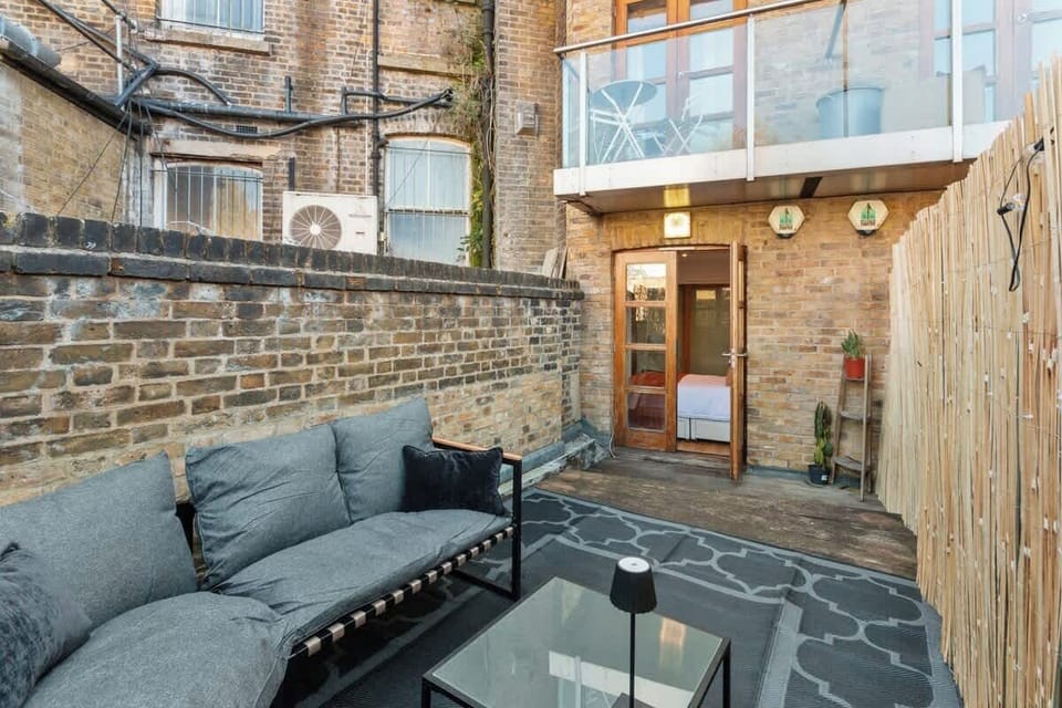 Stylish private patio with outdoor seating and direct access to the apartment. A calm, enclosed space ideal for relaxing, working outdoors, or enjoying a drink after exploring Fulham Broadway.