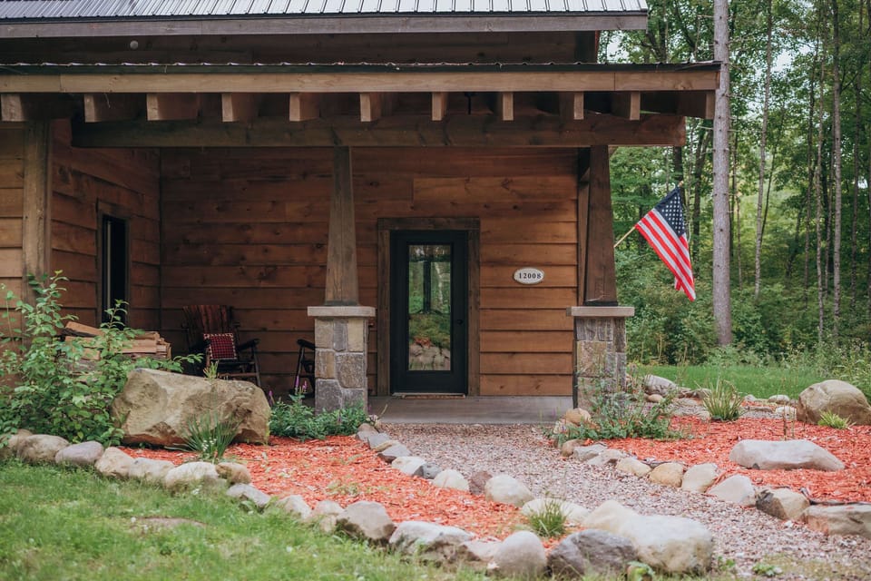 Main entrance to the cabin with covered porch and natural stone details.