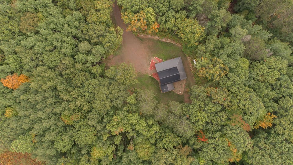 Aerial view showing the cabin tucked into the surrounding woods.