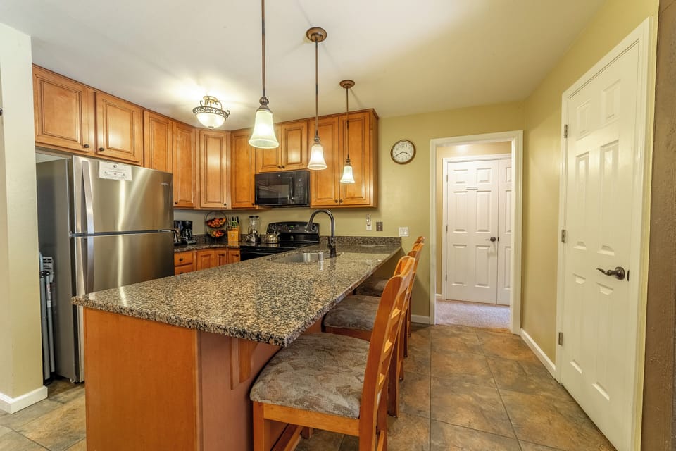 Kitchen with solid stone countertops and breakfast bar seating.