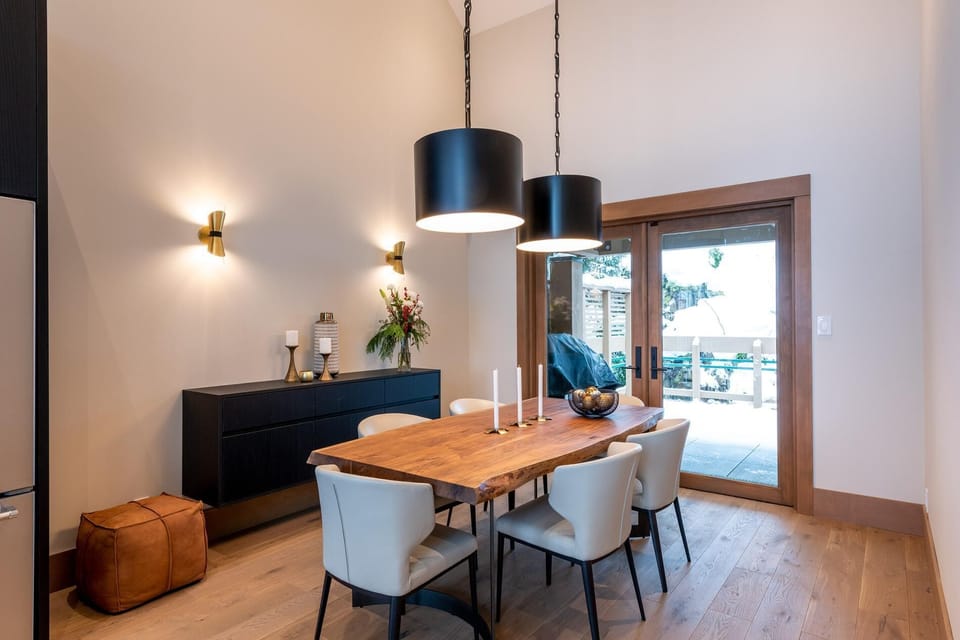 Dining room with live-edge table, lofted ceiling and plenty of mood lighting. The back terrace is a nice large space with seating and hot tub that backs onto the wooded hill.