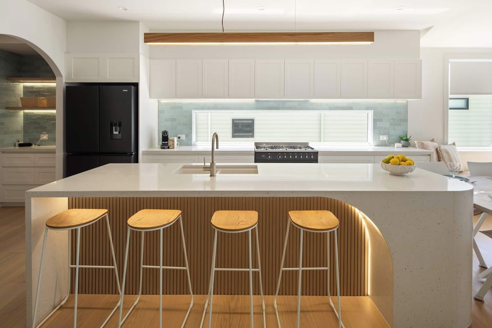 Modern kitchen featuring bar stools, ample counter space, and stylish lighting.