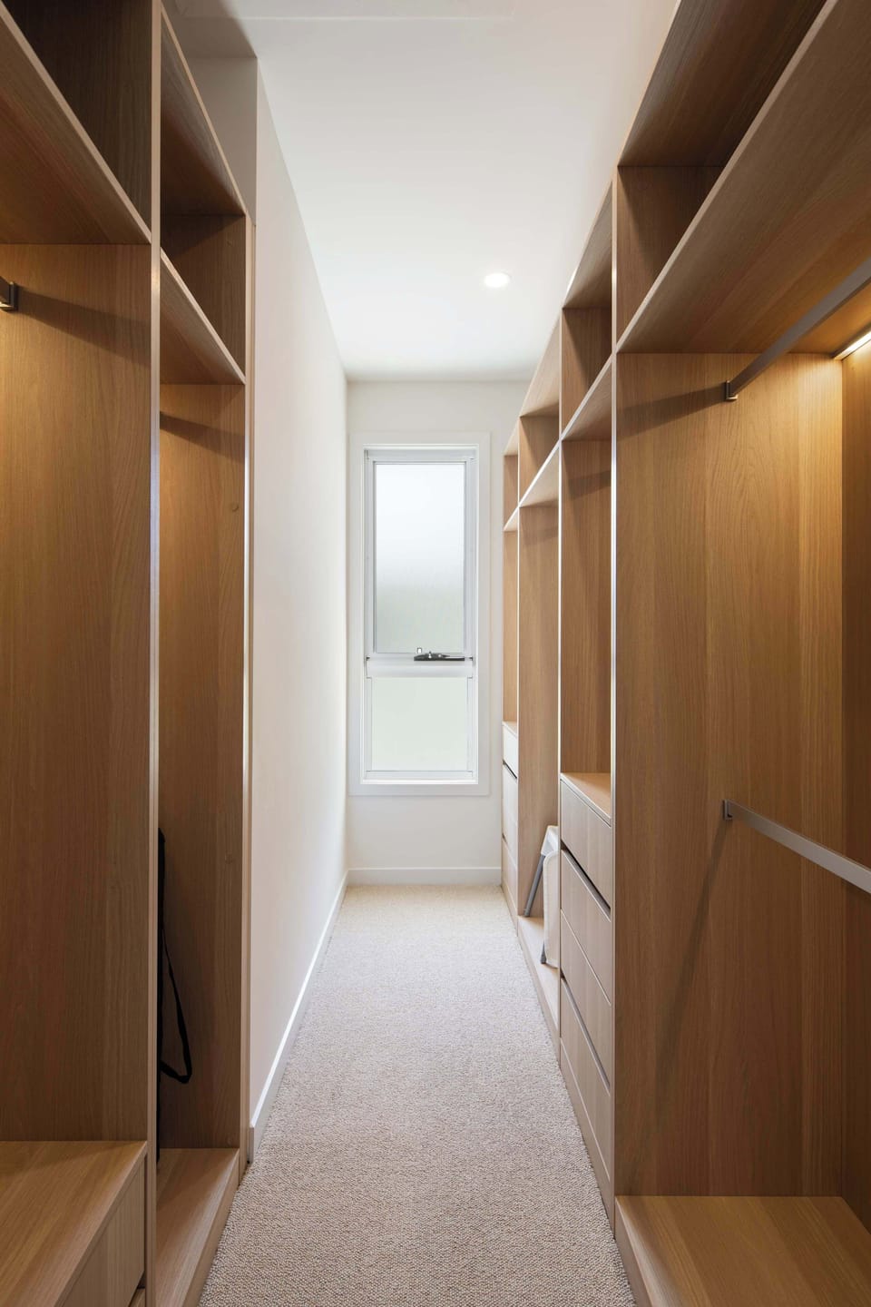 Spacious walk-in wardrobe with ample storage and modern wood finishes.