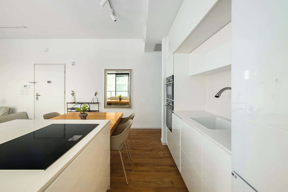 Minimalist lines and integrated appliances create stylish cooking space, ideal before evenings by the sea.