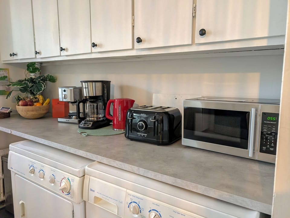 Tout ce dont vous avez besoin pour bien commencer la journée ! Ce comptoir pratique est entièrement équipé d'un micro-ondes, d'un grille-pain, d'une bouilloire électrique et d'une cafetière filtre, avec de nombreuses armoires de rangement au-dessus.