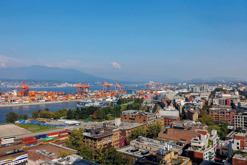 Discover the dynamic mix of urban life and industrial beauty. This wide view shows the city's vibrant neighborhoods and active waterfront, with the port of Vancouver and the surrounding mountains creating an incredible panorama.