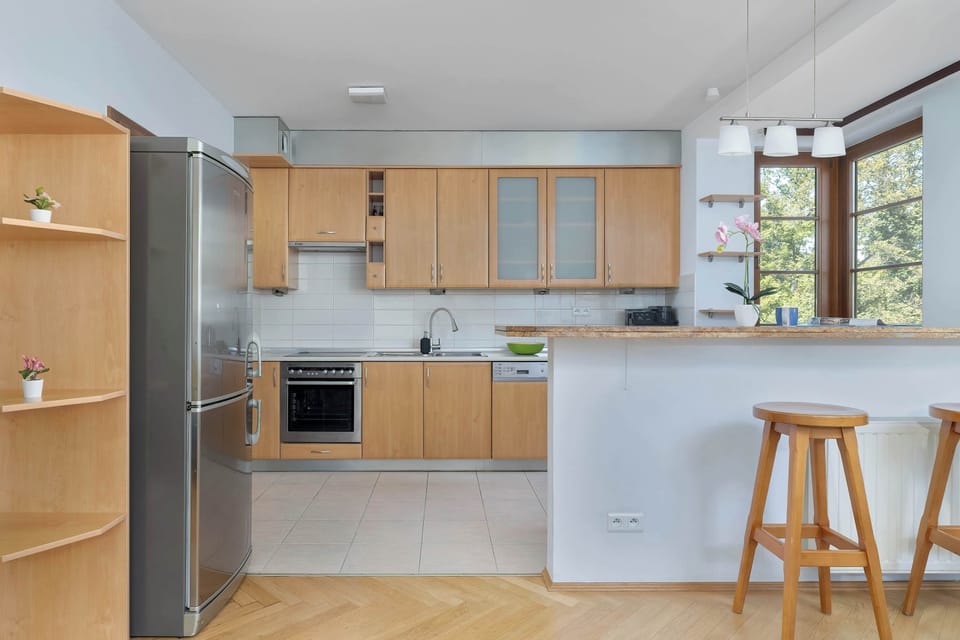 A modern kitchen with light wooden cabinets and a granite countertop. Equipped with appliances, providing a practical cooking area.