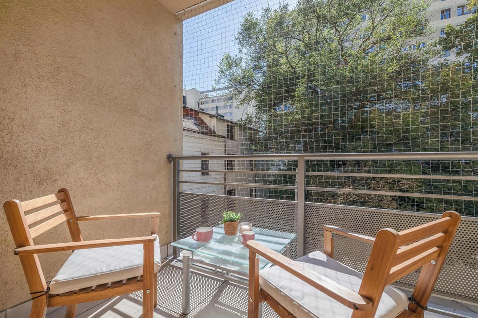 Another view of the balcony with wooden furniture and a small table for drinks or meals. A peaceful spot to unwind.