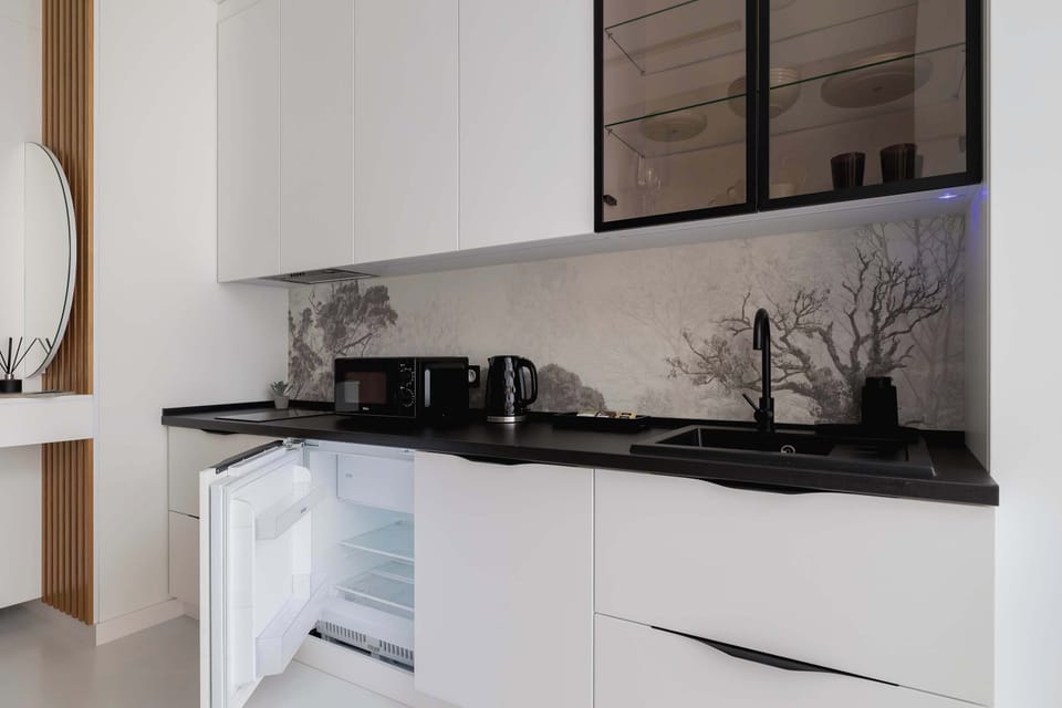 Modern kitchenette with fridge, microwave and functional cabinets.