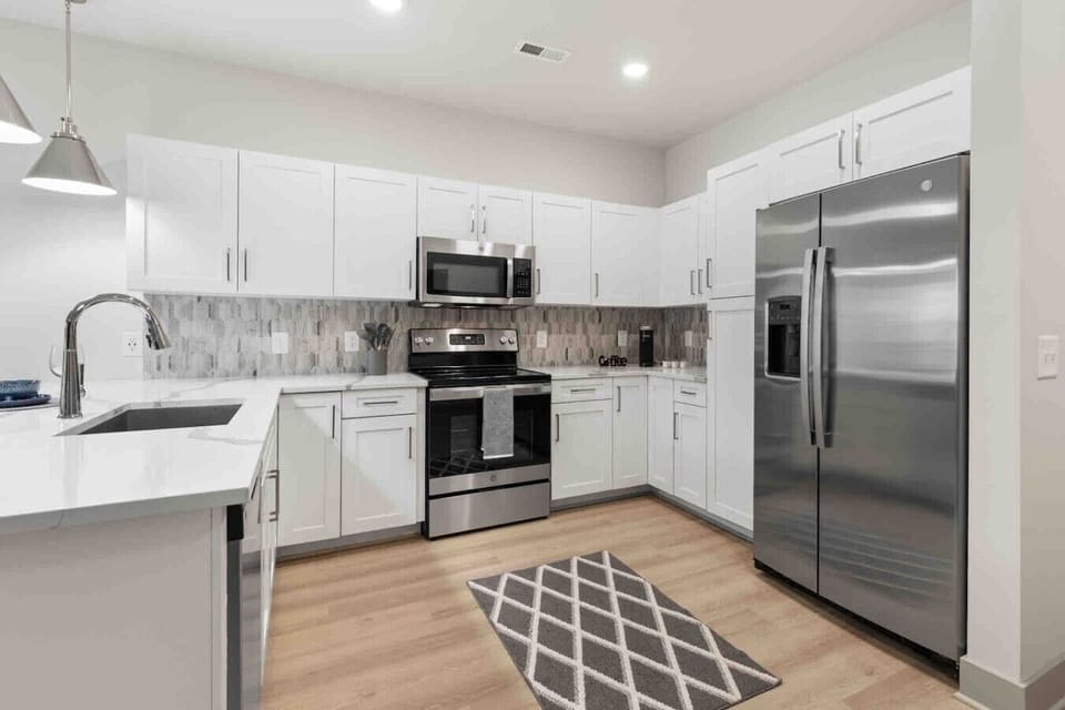 Sleek Modern Kitchen-Contemporary kitchen with stainless steel appliances, ample white cabinetry, and elegant backsplash. Designed with style and function for a comfortable cooking experience.
