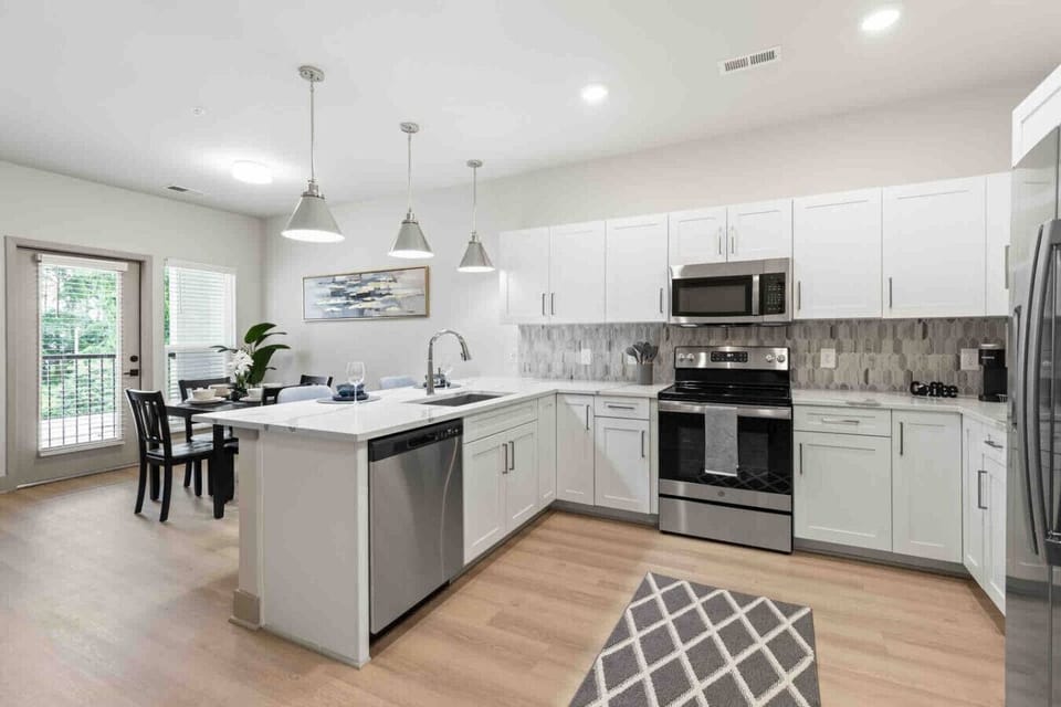 Open-Concept Kitchen-Modern kitchen with stainless steel appliances, white cabinetry, and stylish backsplash. Overlooks the living area with natural light, creating a bright and inviting open layout.