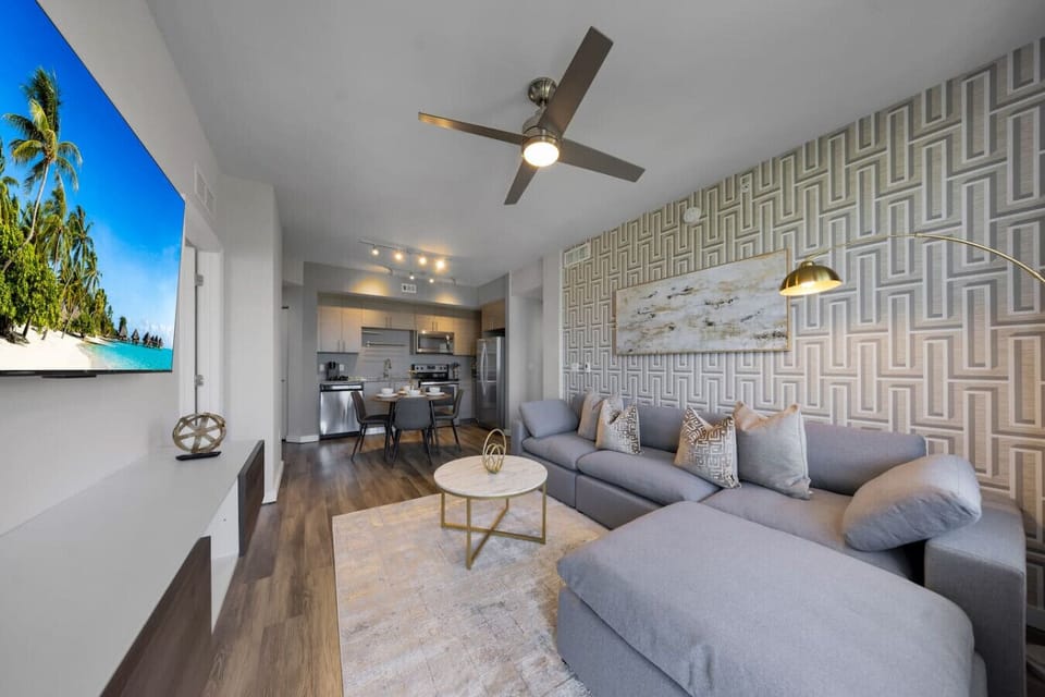Open-Concept Living & Dining Area-Spacious layout with a modern sofa, flat-screen TV, and elegant décor flowing seamlessly into a fully equipped kitchen and dining space, perfect for both relaxing and entertaining.