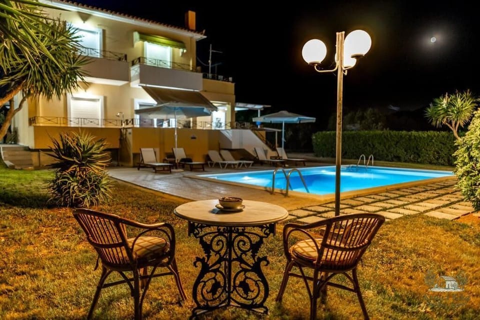 Poolside Dining Area at Night – Cozy outdoor table and chairs by the pool, beautifully lit for evening gatherings.