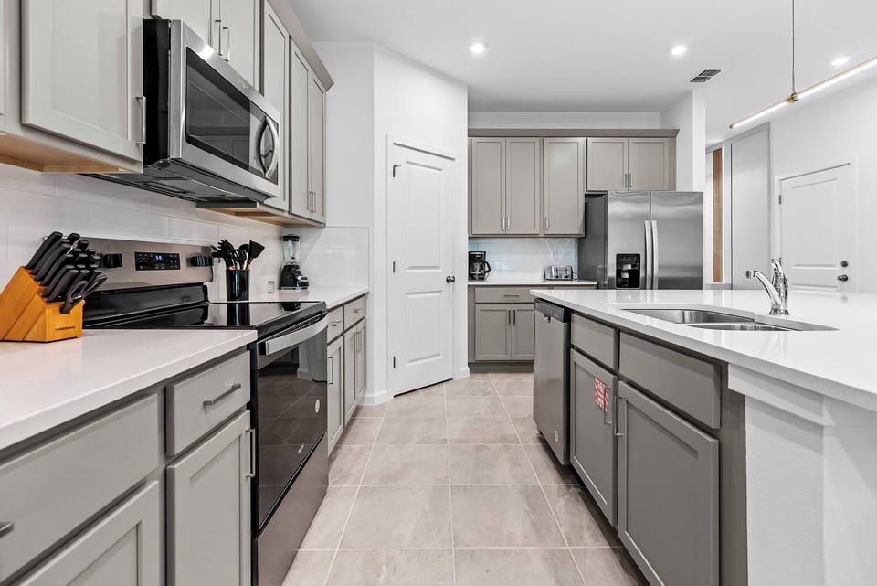Discover a chic kitchen perfect for culinary adventures, with sleek gray cabinets and bright white countertops. Enjoy the modern appliances and bright recessed lighting, ideal for meal prep and casual gatherings.