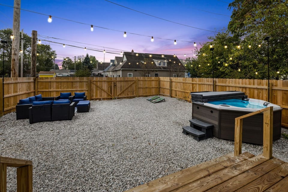 Private backyard oasis with hot tub, lounge seating, and string lights.