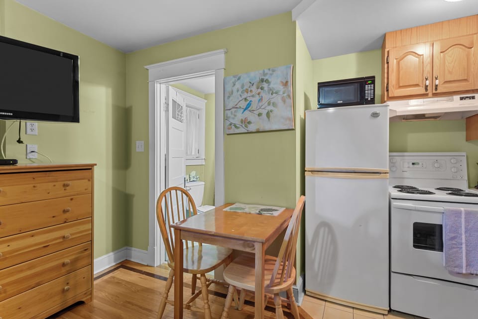 Enjoy your morning coffee at this charming wooden dining set located conveniently between the kitchen and the private bathroom entrance.