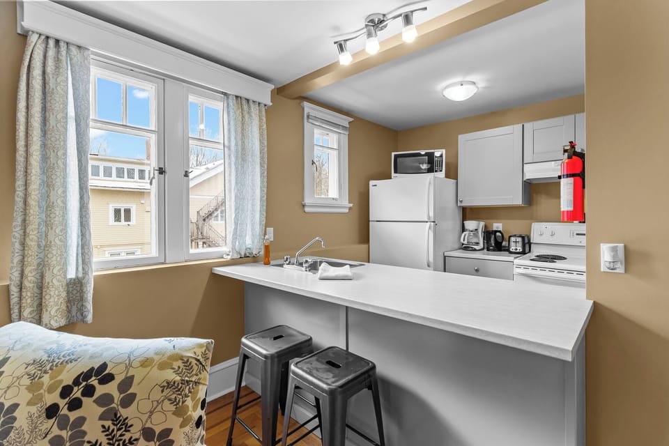 Bright Kitchen with Breakfast Bar. Prepare meals in this airy kitchen featuring modern appliances, a breakfast bar with seating, and large windows for natural light.