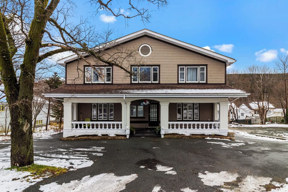 Historic Property Charm: A view of the stunning multi-unit home featuring classic architecture, a grand covered porch, and a spacious front driveway.