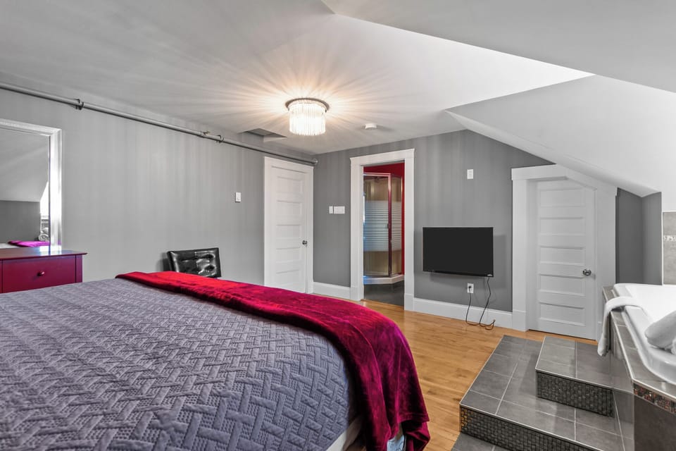 Modern grey bedroom with direct access to a vibrant red en-suite bathroom.