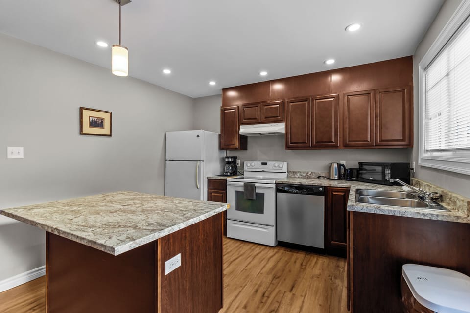 Kitchen View 2: Chef-ready kitchen with ample cabinet space, full-sized refrigerator, and electric range. Includes a breakfast bar island for extra seating.