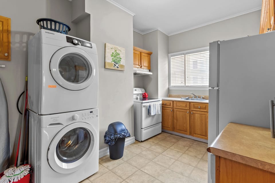 Convenient in-unit laundry area featuring a stacked washer and dryer. The space is located right next to the kitchen, making it easy to manage chores while cooking or relaxing during your stay.