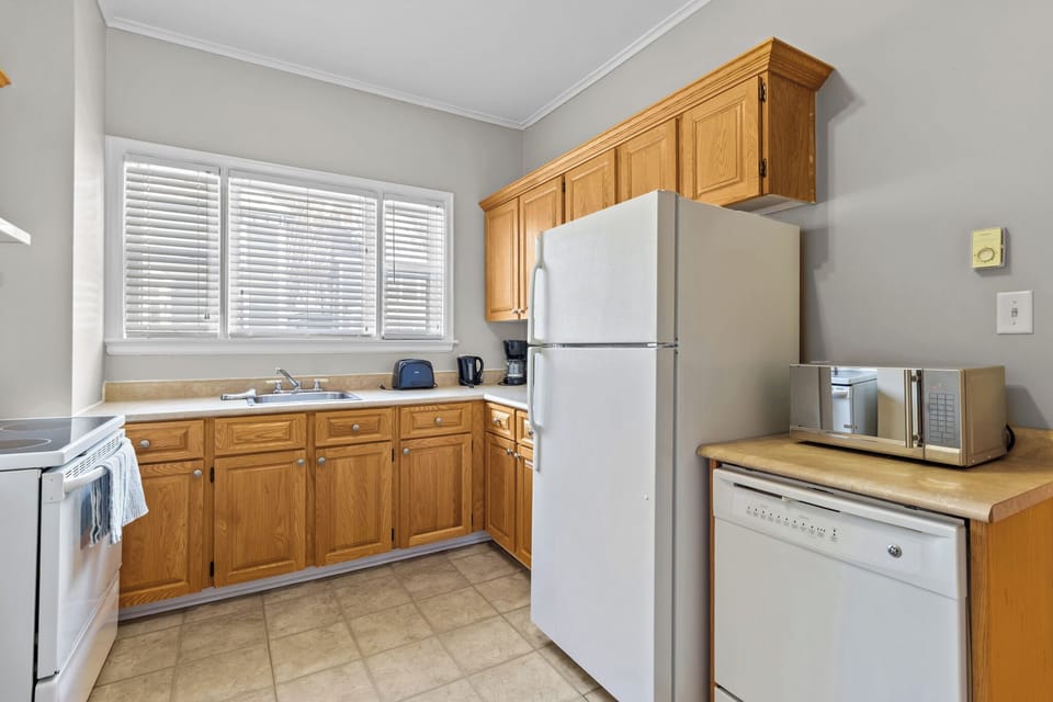 Modern kitchen detail featuring ample counter space, a large refrigerator, and a dishwasher for easy cleanup. Essentials like a toaster and kettle included.