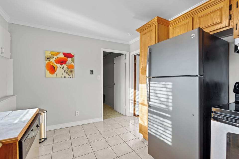 A functional view of the kitchen area showing the tiled floor transition, full-sized refrigerator, and easy access to the rest of the home.