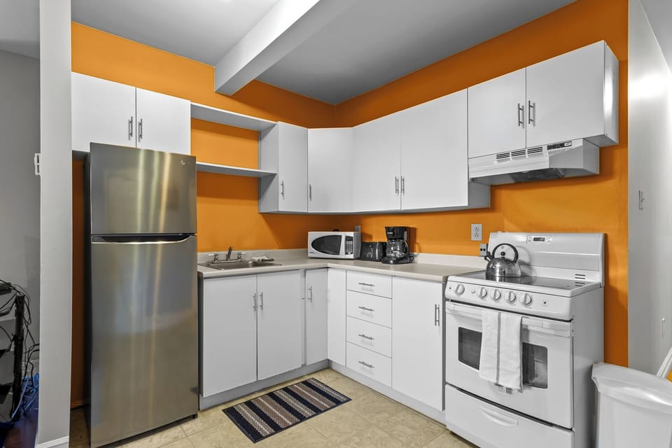 Cook your favorite meals in this clean, fully-equipped kitchen with white cabinetry, stainless steel fridge, microwave, and plenty of counter space.