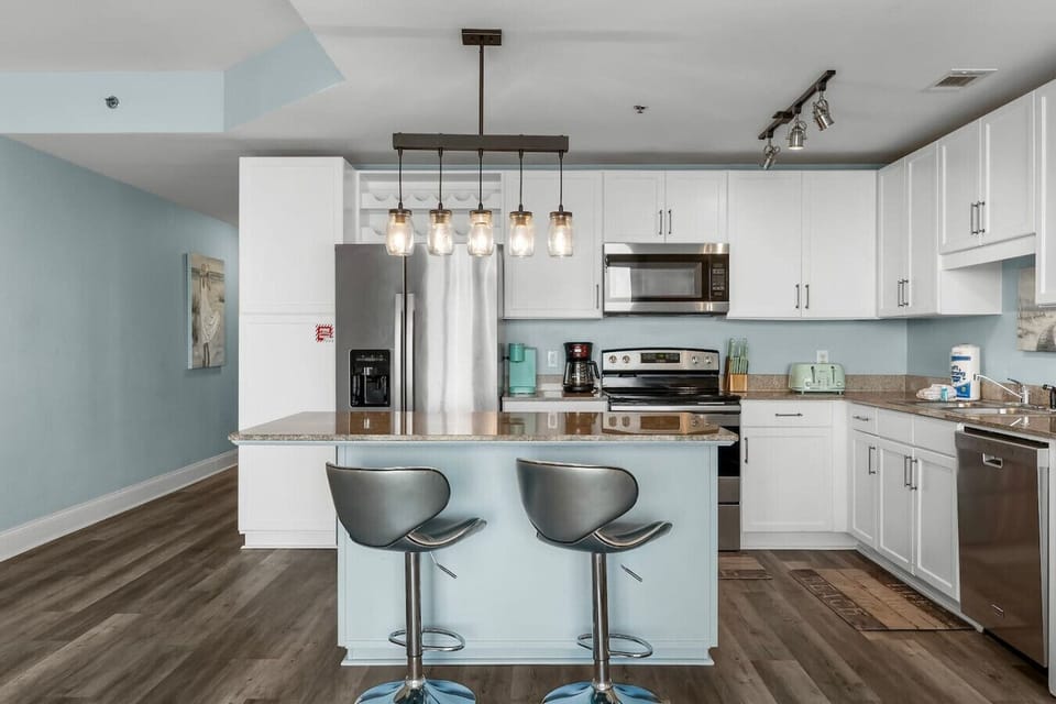 This fully equipped kitchen features stainless steel appliances, a spacious island with bar seating, and stylish lighting for cooking and entertaining