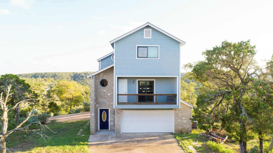 This three-story home features a one-car garage, covered carport for two, and stunning Hill Country views.