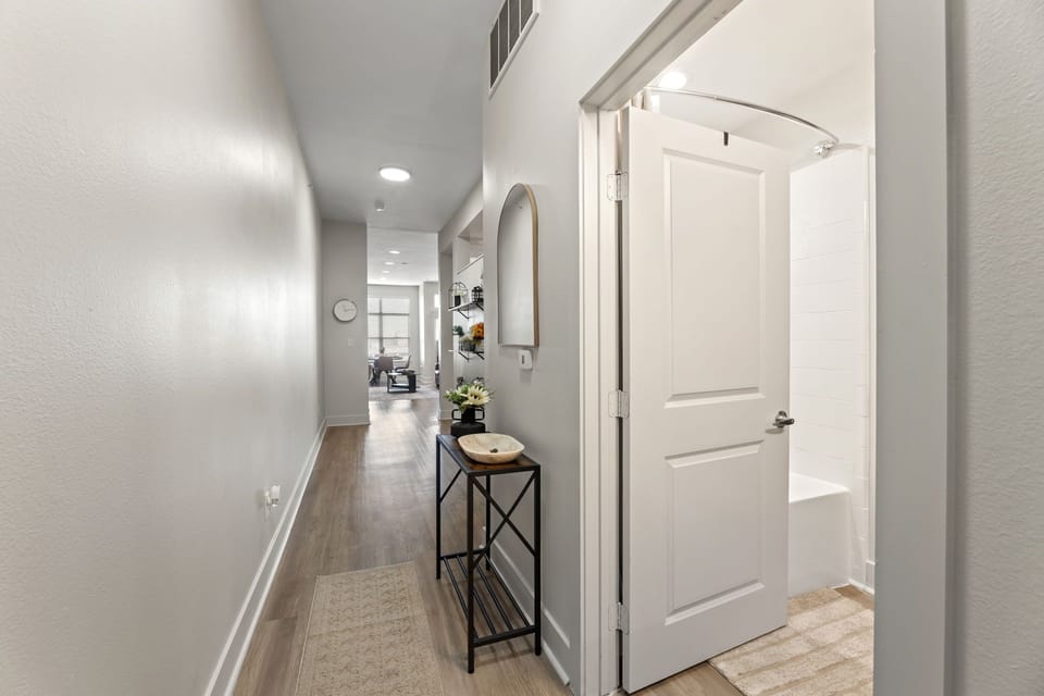 Bright entryway with modern décor, mirror, and accents leading to living area.