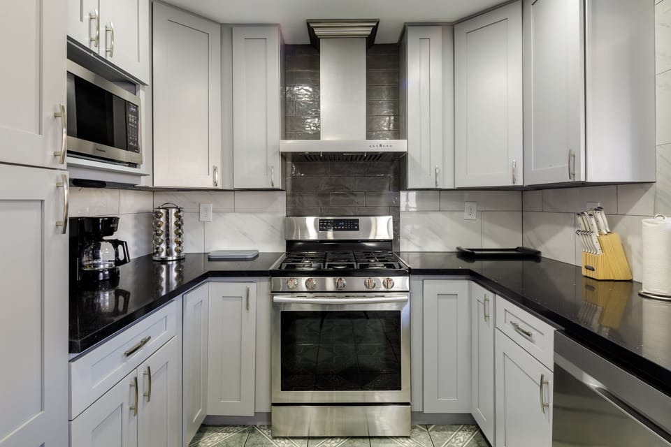 Modern kitchen with deep stainless sink, pull-down faucet, and black quartz counters.