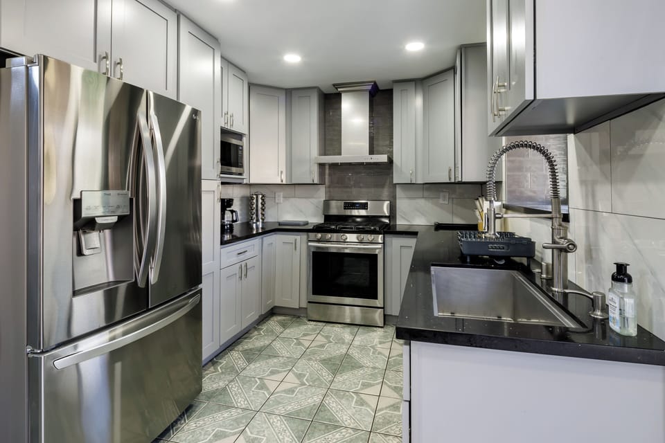 Modern kitchen with deep stainless sink, pull-down faucet, and black quartz counters.